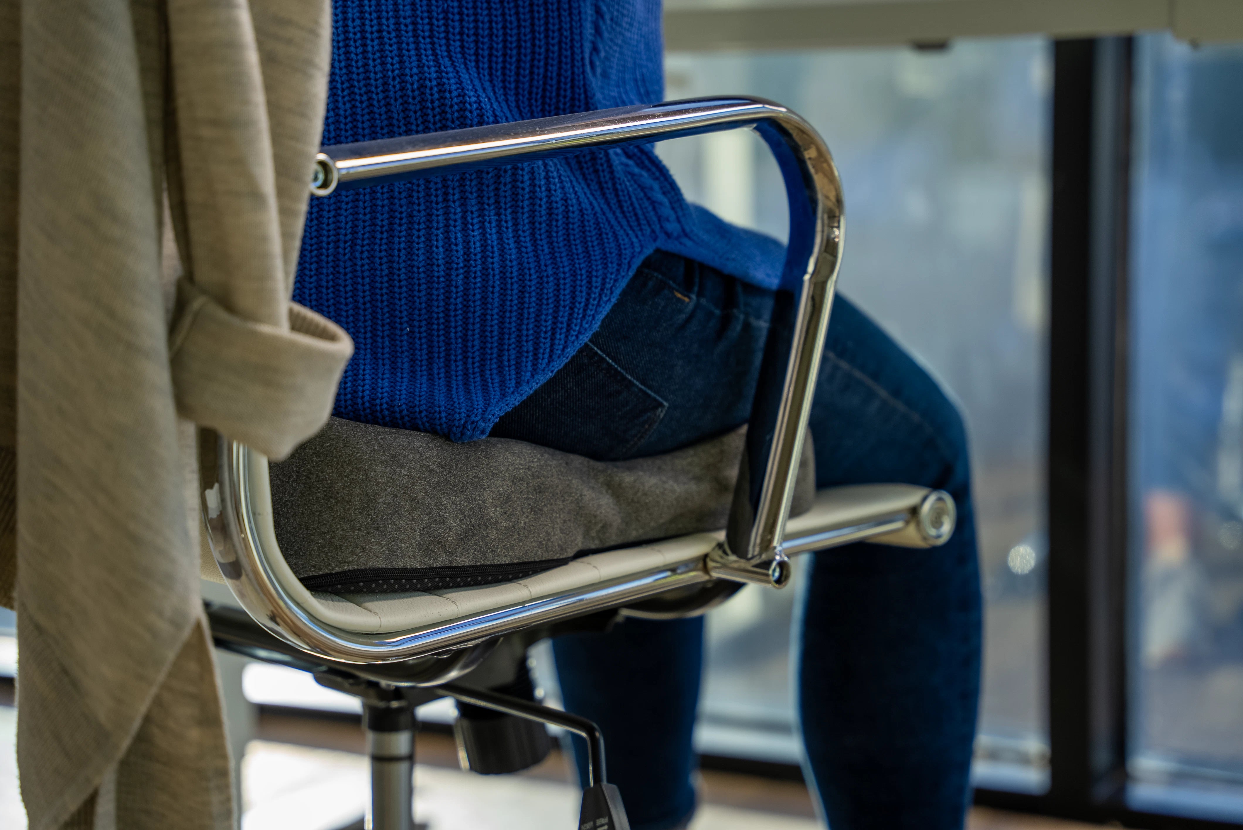 Person sitting on a Sutera ortho cushion in a chair.