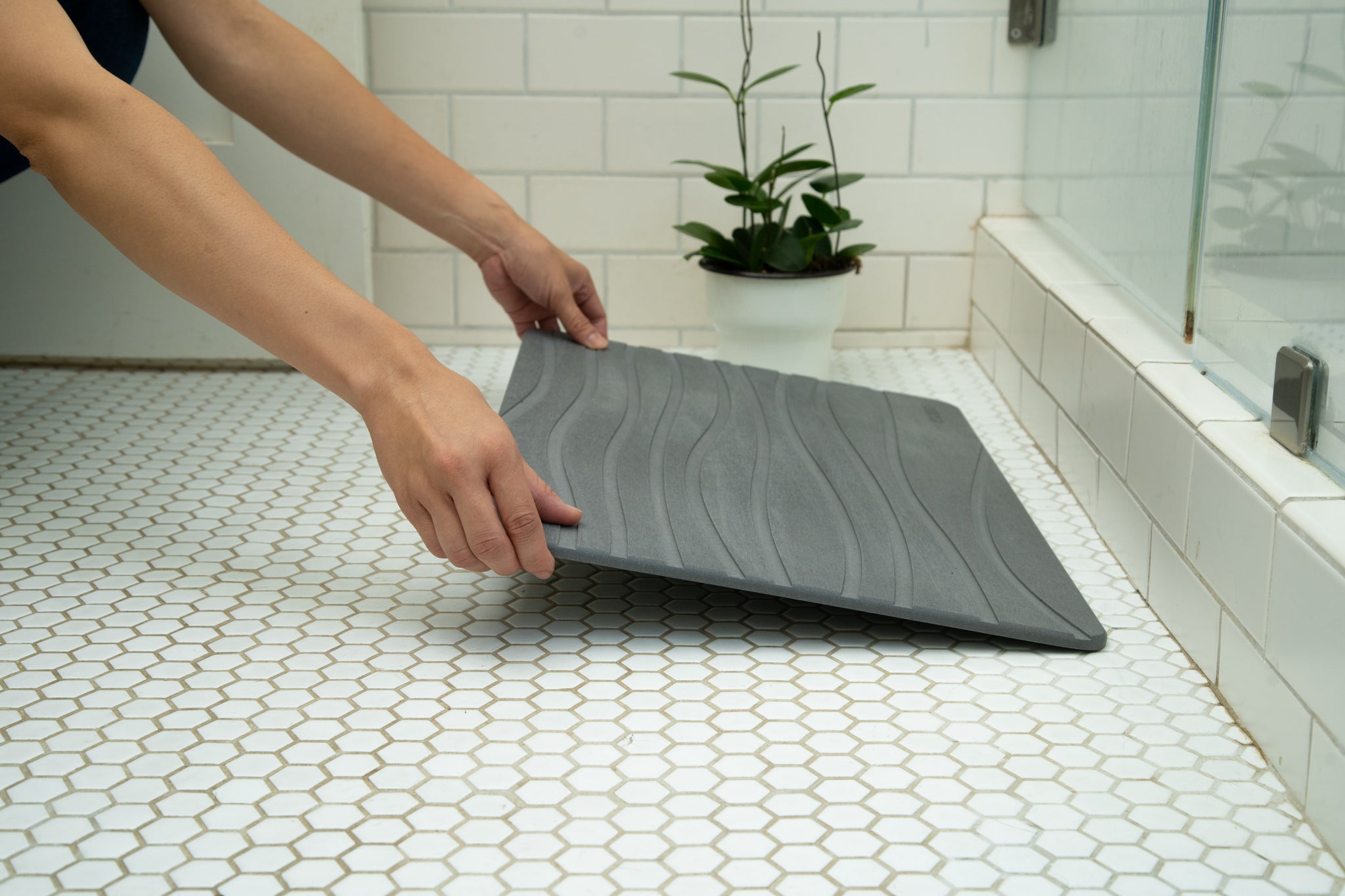 Person placing a stone bath mat outside their shower.